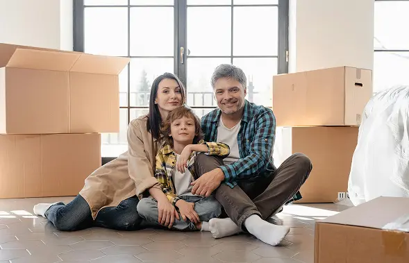 family sitting on floor with moving boxes around happy their affordable life insurance quotes secured them