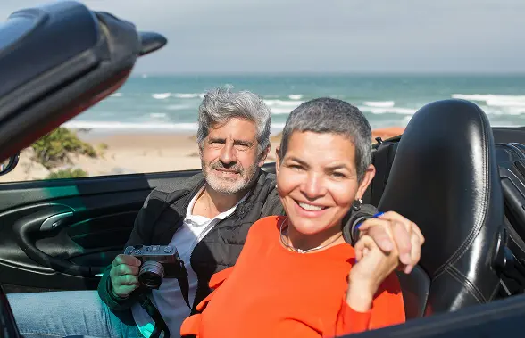 happy retired couple in nice car by beach from great employee benefits