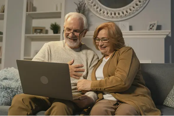 happy retired couple on coach surprised by what their new Medicare plan provides